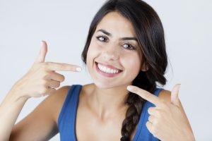 Woman Pointing at Her Smile After Orthodontic Treatment